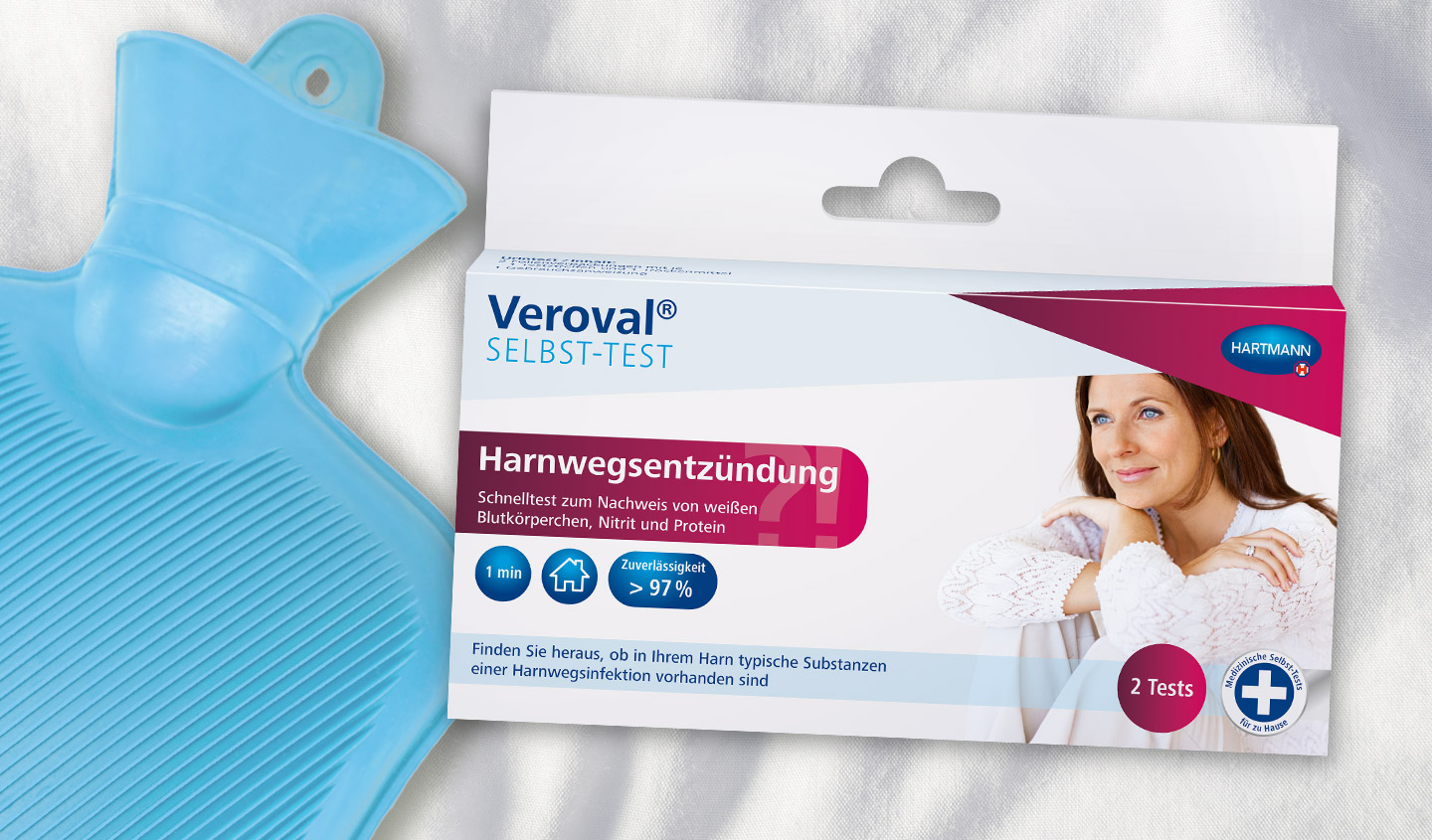 Verpackung des Veroval® Selbst-Tests Harnwegsentzündung liegt neben einer blauen Wärmflasche.